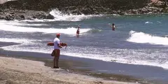 Un socorrista observa a dos bañistas en el agua, en una playa con oleaje y fuertes corrientes.