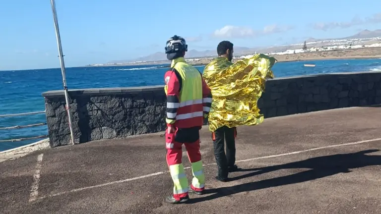 Imagen de uno de los bomberos que también acudió al rescate atendiendo a una de las personas que naufragó.