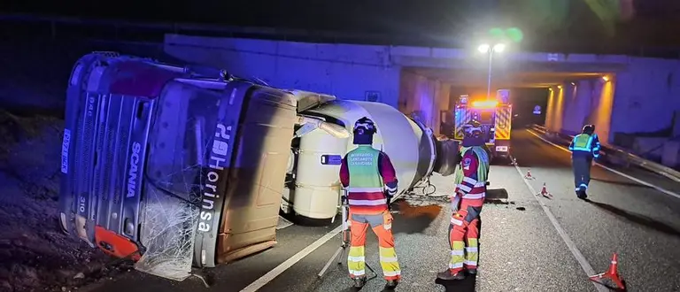 Los bomberos trabajando tras el vuelco de la hormigonera.