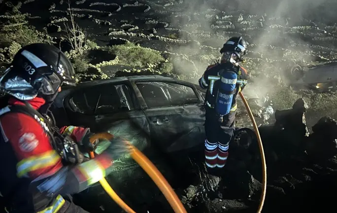 Momento en el que los bomberos tratan de apagar el fuego de uno de los veh&iacute;culos.
