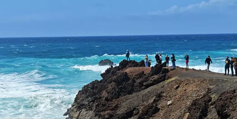 Imagen de personas que tratan de acercarse lo m&aacute;ximo al mar para fotografiar las olas