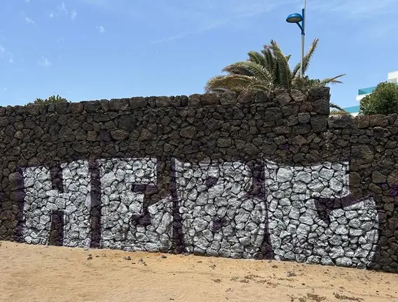 Imagen de una de las pintadas gigantes que han hecho en la piedra volc&aacute;nica de la playa