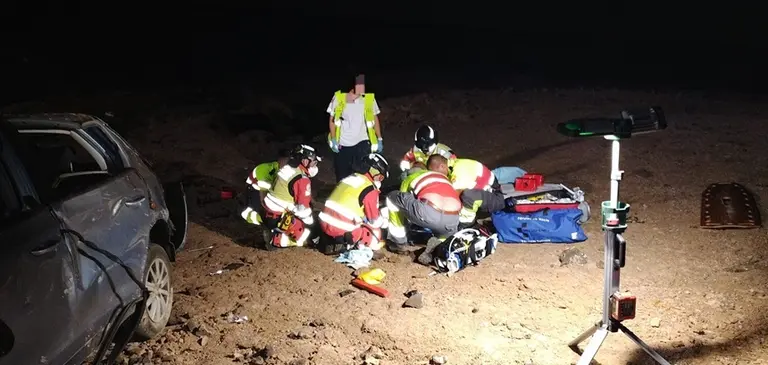 Sanitarios y bomberos atendiendo a uno de los accidentados que se encontraba junto al veh&iacute;culo.