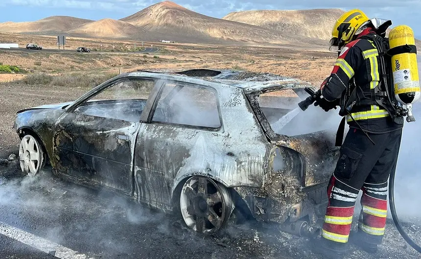 Operario de los bomberos apagando el fuego dentro del vehículo en la entrada a Costa Teguise.