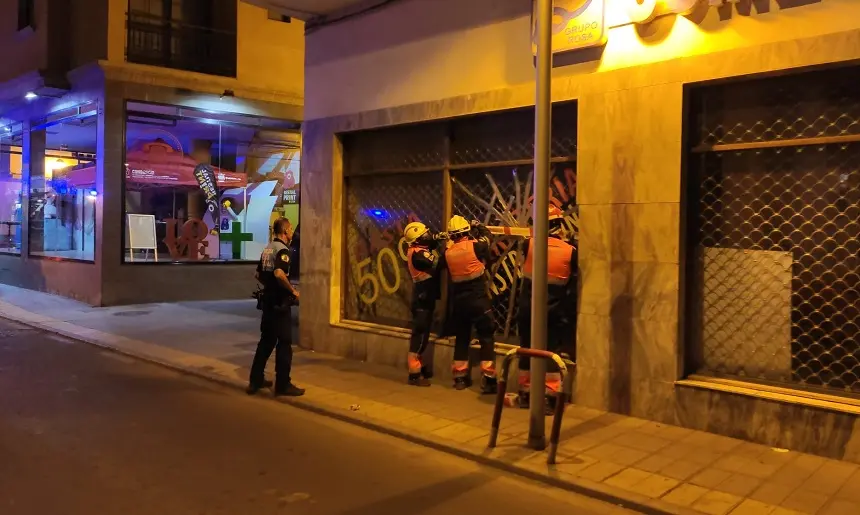 Bomberos del Consorcio durante la reparación del cristal del escaparate dañado.