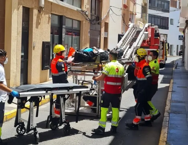 Momento del traslado del enfermo entre el personal sanitario y los bomberos