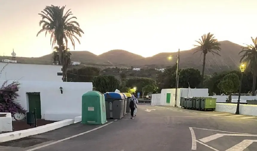 Escolares caminando por la carretera porque los contenederos ocupan el camino