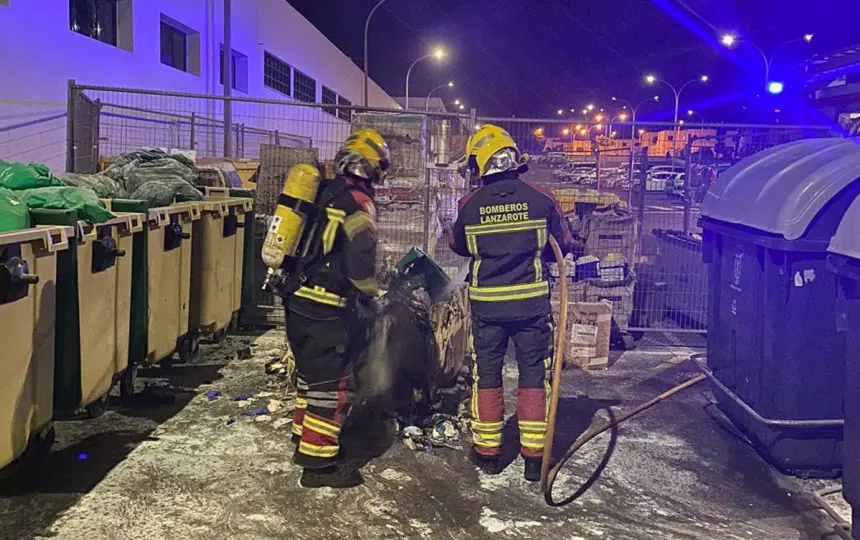 Imagen de los bomberos apagando el fuego situado en un contenedor.