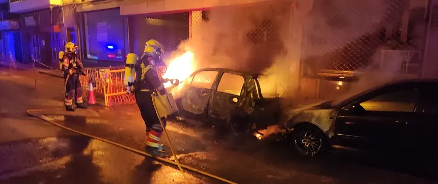 Imagen de los bomberos intentando apagar el fuego en los vehículos.