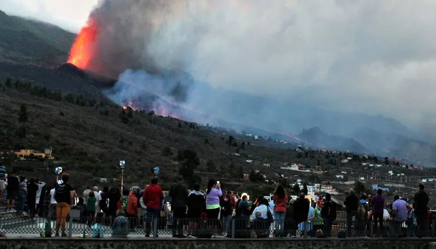 Imagen de la gente viendo el volcán en plena erupción.