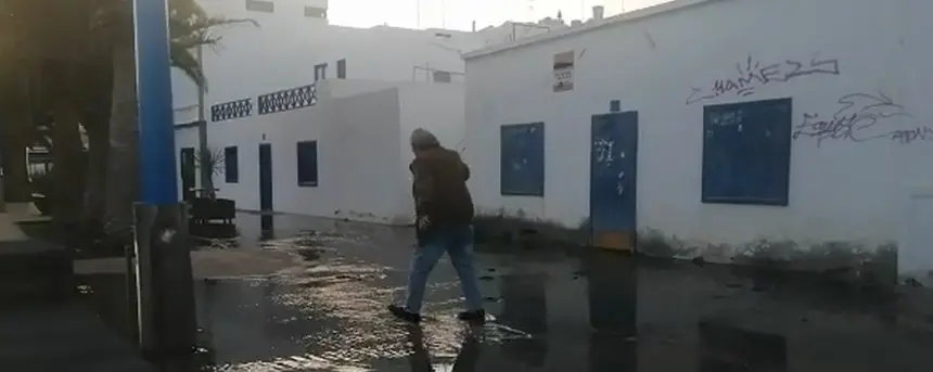 Imagen de la zona de la rotura con un vecino que trataba de sortear el charco de porquería. 