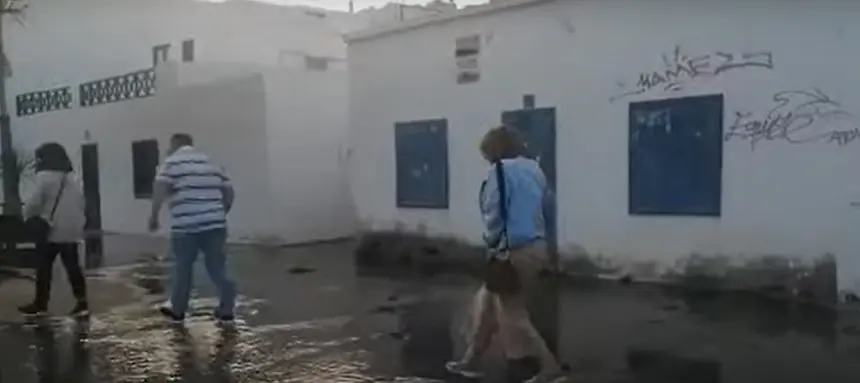Imagen de unos turistas esta semana pasando por encima de la tubería rota en el Charco. 