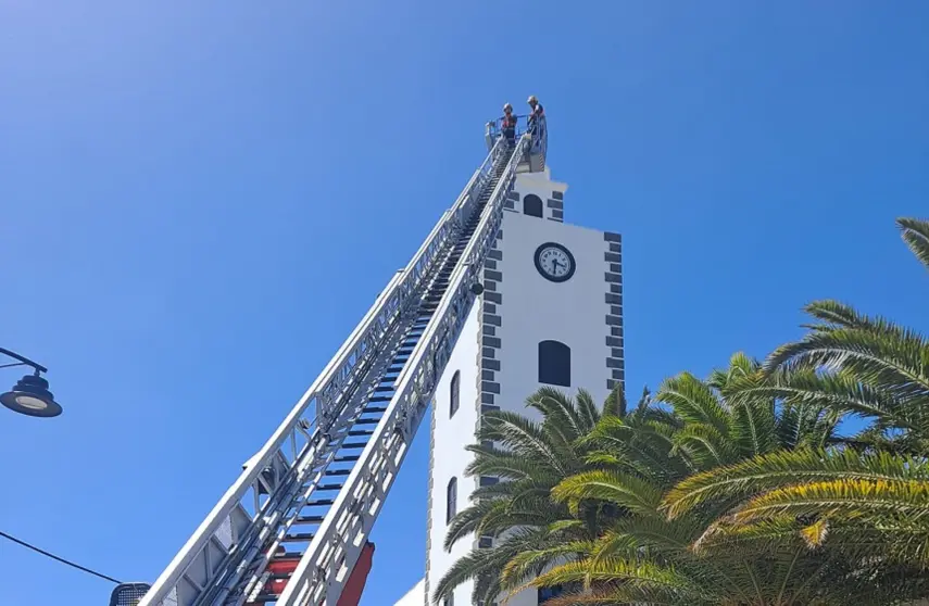 Bomberos del Consorcio retirando el elemento de madera de lo alto de la torre del Ayuntamiento de San Bartolomé.