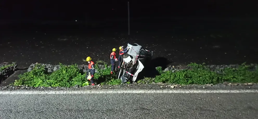 Imagen de los bomberos colocando la cinta alrededor del vehículo accidentado.