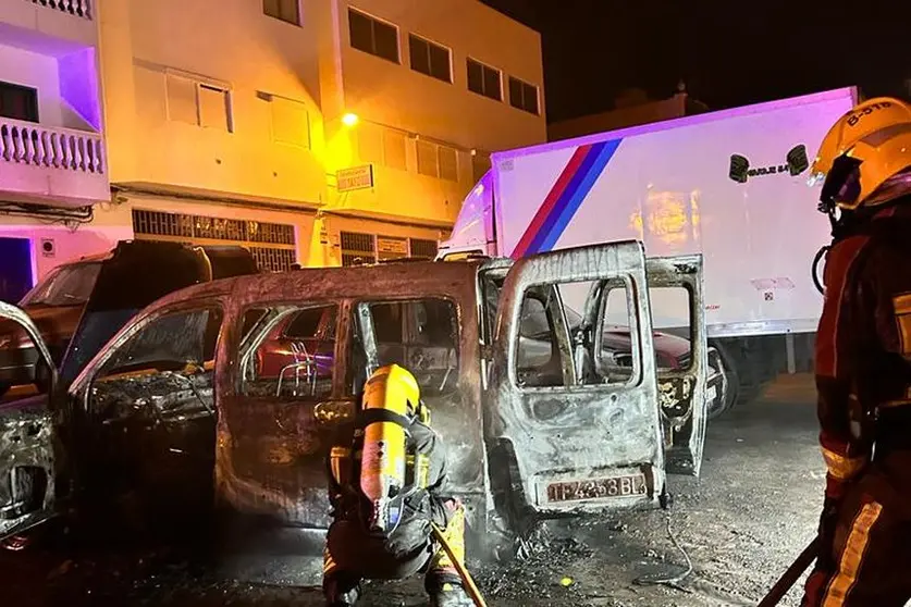 Los bomberos intentando sofocar el incendio de los vehículos