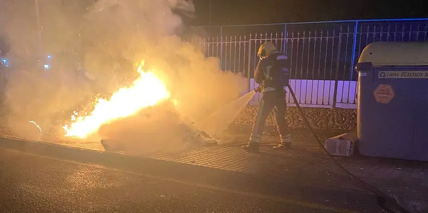 Bombero intentando apagar el fuego que estaba quemando un contenedor.