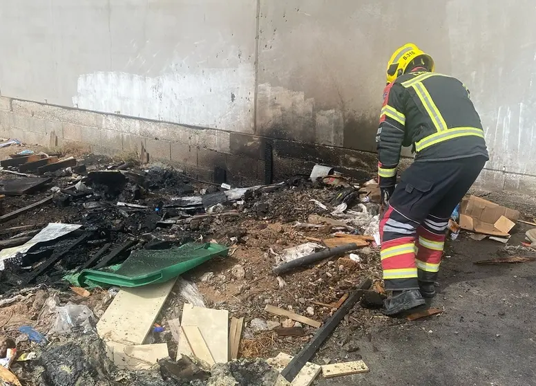 Bombero del Consorcio de Seguridad y Emergencias junto a los restos del contenedor.