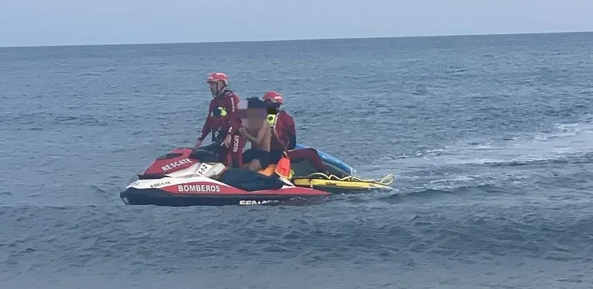 Instante en el que los bomberos trasladan al menor a la orilla