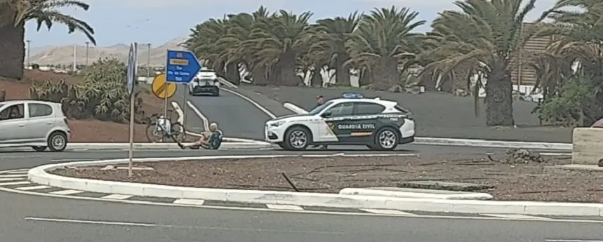 Ciclista afectado en el suelo junto a la Guardia Civil.