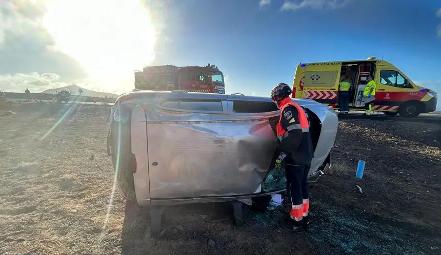 Los bomberos atendiendo al vehículo siniestrado.