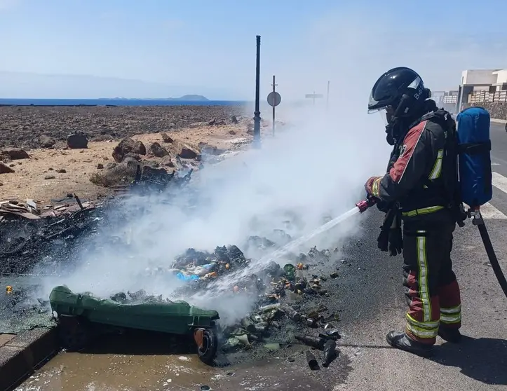 Imagen de los bomberos tratando de terminar de apagar uno de los contenedores incendiados