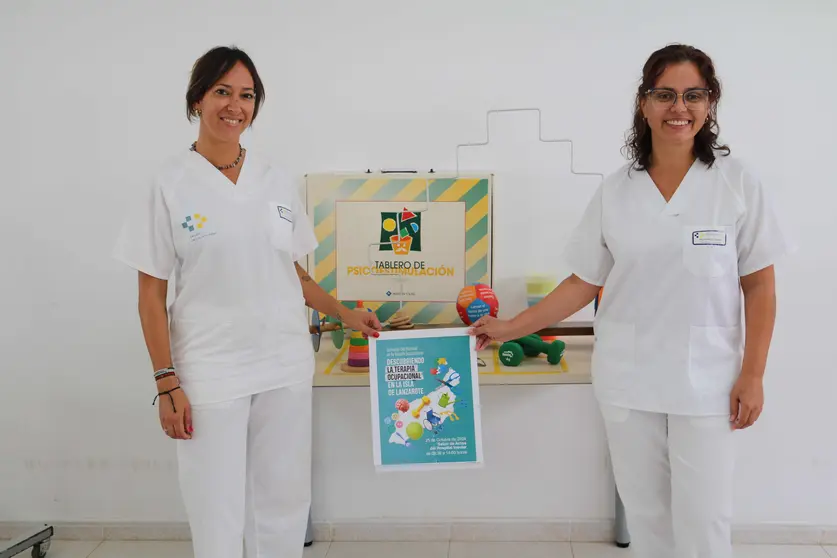 Sanitarias junto al cartel de la jornada de terapia ocupacional.