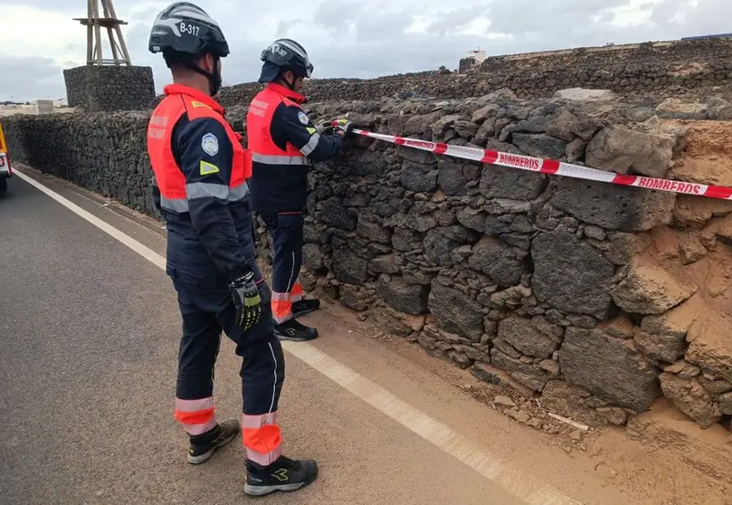 Los bomberos tras reparar el deteriorado muro.