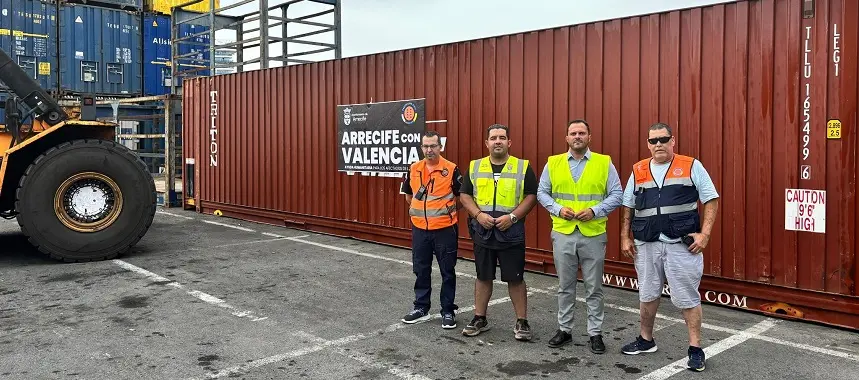 Yonathan de León y Kevin Cortés, junto a efectivos de Protección Civil, hoy en el puerto de Los Mármoles. De fondo el contenedor con ayuda humanitaria para Valencia