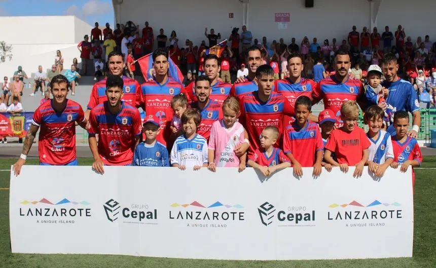 Los jugadores con parte de los aficionados al inicio del encuentro.