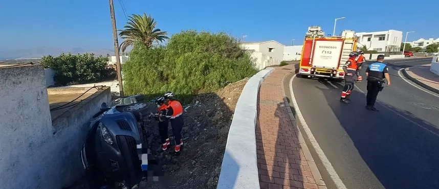 Bomberos junto al vehículo accidentado en Tías.