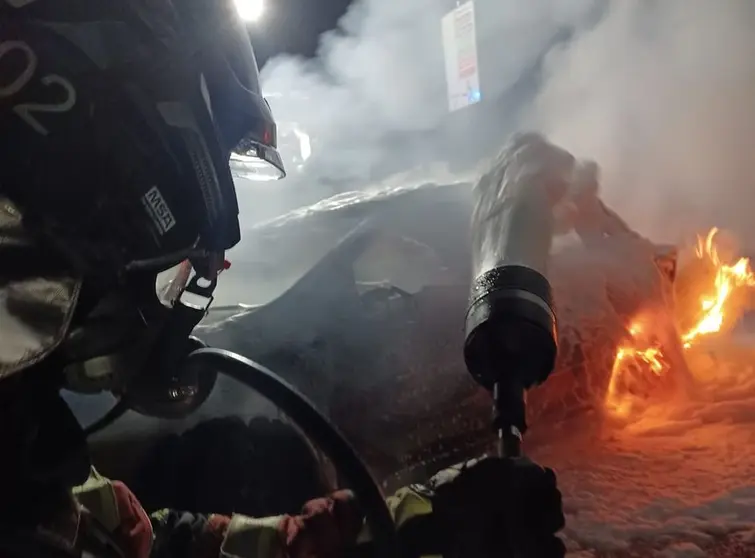 Instante en el que uno de los bomberos lanza la espuma contra el fuego del vehículo