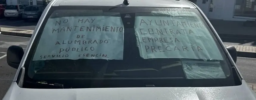 Carteles de protesta de los trabajores de la empresa de alumbrado de Tías en un vehículo.