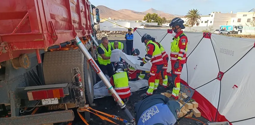 Bomberos durante la operación de extracción del cuerpo sin vida del fallecido de debajo del camión.