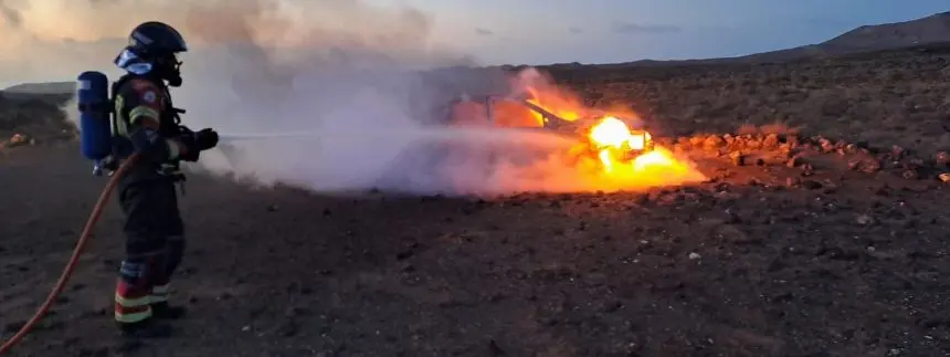 Un bombero extingue el fuego del coche en llamas.