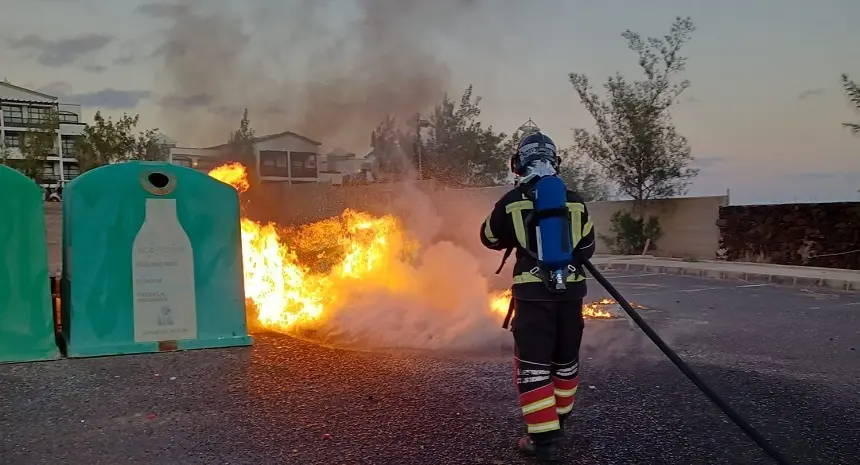 Bombero apagando el fuego que afectaba a dos contenedores.