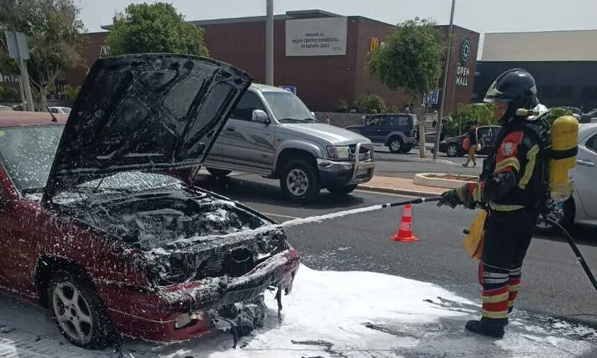 Bombero sofocando las llamas dentro del vehículo.