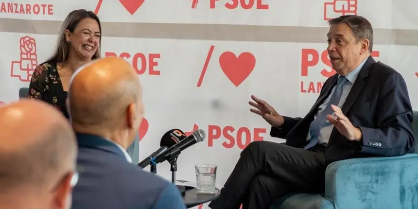 La secretaria general del PSOE sonríe durante la intervención del ministro.