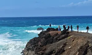 Imagen de personas que tratan de acercarse lo m&aacute;ximo al mar para fotografiar las olas