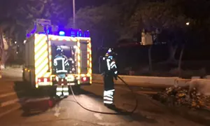 Bomberos del Consorcio de Seguridad y Emergencias apagando las llamas en un contenedor.