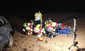 Sanitarios y bomberos atendiendo a uno de los accidentados que se encontraba junto al veh&iacute;culo.