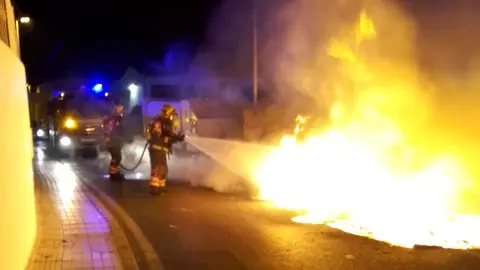 Momento en el que los bomberos tratan de sofocar el incendio cerca de una zona habitada