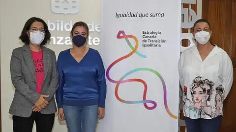 Silvia Jaén, María Dolores Corujo y Myriam Barros junto al cartel de la Estrategia Canaria de Transición Igualitaria.