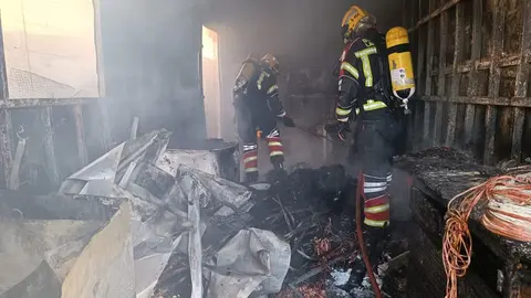 Bomberos del Consorcio extinguiendo el fuego dentro del contendor de obra.