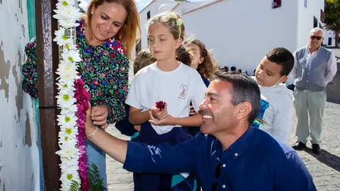 Oswaldo Betancort, alcalde Teguise, y Nori Machín, concejala de Cultura, junto a una niña colocando flores en una cruz.