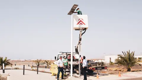 Oswaldo Betancort y Eugenio Robayna junto a un operario realizando las labores de instalación del alumbrado público.