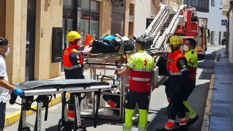 Momento del traslado del enfermo entre el personal sanitario y los bomberos