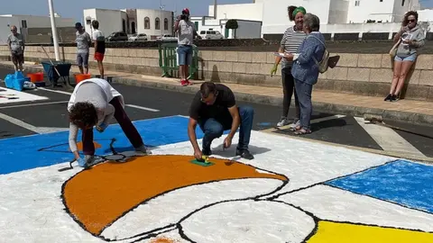 Imagen de gente trabajando en una de las tradicionales alfombras de sal.