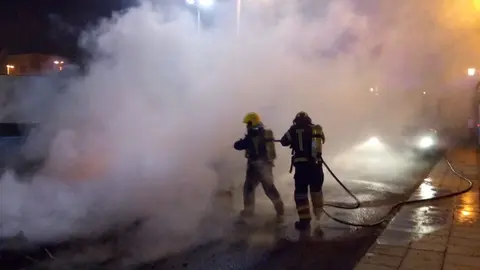 Imagen de los bomberos actuando en el incendio de tres contenedores en las cuatro esquinas.