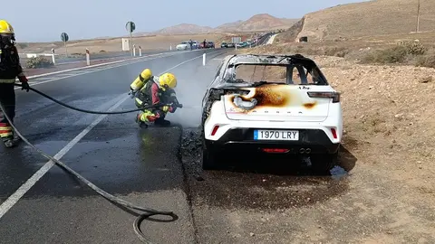Imagen de los bomberos extinguiendo el fuego en el coche.