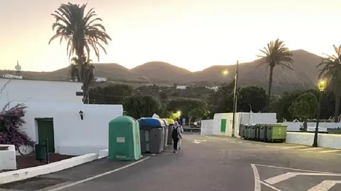 Escolares caminando por la carretera porque los contenederos ocupan el camino
